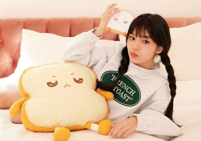 Jessica Vu posing on a bed with Resting Bread Face from the brand, DeliVury.